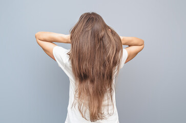 Fototapeta premium Natural long female hair. Hands behind head. Rear view on gray background, isolated. Hair treatment.