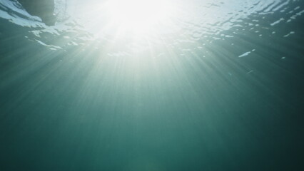 Amazing bright underwater light with sun rays in transparent blue ocean. Sun underwater beams rays sun shine underwater relaxing ocean scenery backgrounds. Copy space background. Beautiful reflection