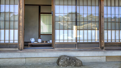 Naklejka premium Japanese style house with large windows and wooden planks, tea sets inside, traditional architectural style,