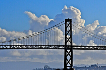 West tower of San Francisco Oakland Bay Bridge silhouetted by billowing clouds 
