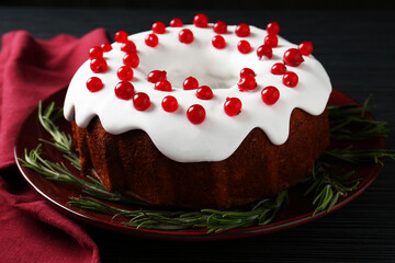 Tasty Christmas cake with red currants and rosemary on black table, closeup