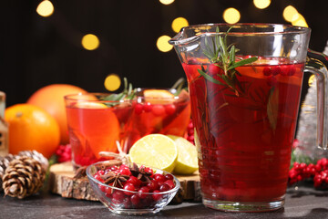 Tasty punch drink and ingredients on dark table against blurred lights, closeup