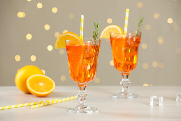 Tasty Christmas cocktail in glasses on white wooden table against blurred lights