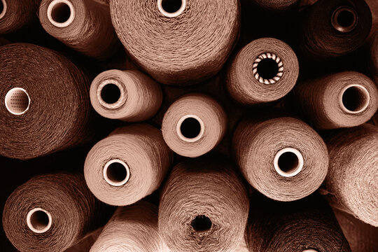 Close-up image showcasing multiple yarn spools in an array of earthy tones. Demonstrating color of 2025 year.