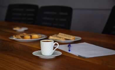 Coffee cup cookies and clipboard with pen on wooden table in office