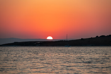Naklejka premium Fiery sunrise with sailboats anchored near island Otocic Trumbuja in bay Kamenjak national park, Adriatic Mediterranean Sea, Croatia. Seen from coastal town Premantura, Istria peninsula, Europe
