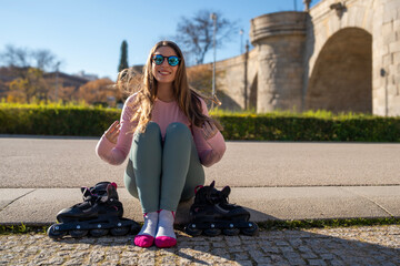 Young sporty woman resting after inline skating in the city park