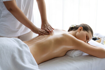 Caucasian woman customer enjoying relaxing anti-stress spa massage and pampering with beauty skin recreation leisure in day light ambient salon spa at luxury resort or hotel. Quiescent