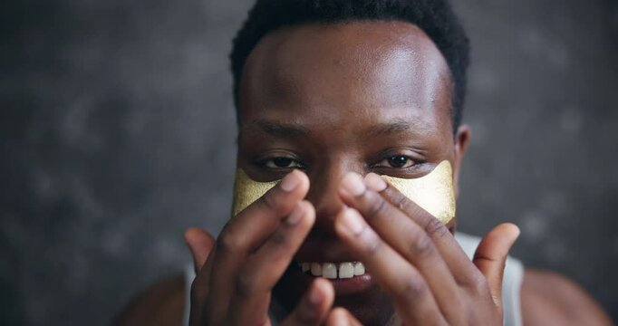 Face, black man and smile with eye patches for skincare, hygiene and glow in dark background. Male person, facial mask and happy or satisfied with cosmetics product for self care and grooming