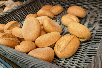 Fresh Graham rolls in a wicker basket. Golden brown whole-grain rolls stacked on display. Bakery shelf with crisp buns for breakfast or sandwiches. Perfectly baked healthy bread option.
