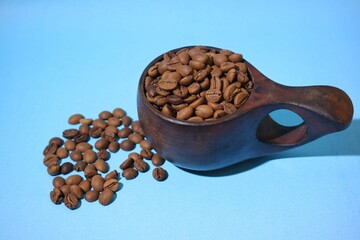Coffee beans and wooden cup isolated on blue background