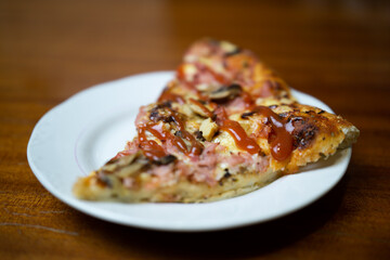 Slice of pizza with ketchup on a white plate