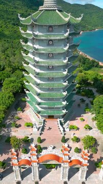 The Thap Xa Loi temple in Da Nang features a multilevel pagoda overlooking lush greenery and blue waters, symbolizing tranquility and spirituality.