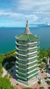 The stunning Thap Xa Loi temple in Da Nang showcases intricate architecture against a backdrop of deep blue water and lush greenery.