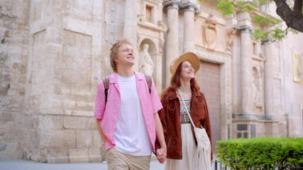 Joyful young couple happily poses together in front of a historic building, capturing a beautiful moment of adventure and love while enjoying their time in this exciting location of culture