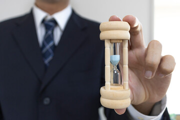 スーツを着て砂時計を持つ男の手（30代、日本人）