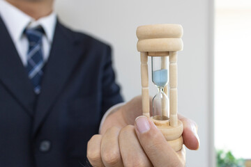 スーツを着て砂時計を持つ男の手（30代、日本人）