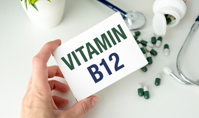 A hand holding a white card that says Vitamin B12