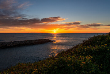 Fototapeta premium Atardecer vibrante sobre el mar con un cielo lleno de colores cálidos y reflejos dorados en el agua.