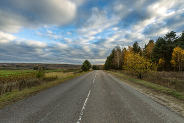 A road with trees in the background and a cloudy sky