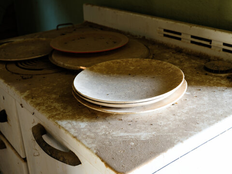 Dusty dinner plates stacked on a stove in an abandoned house near Lake Valley, New Mexico