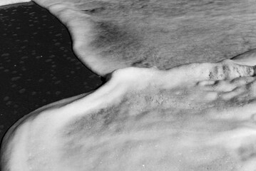 Black and white study of foamy waves overlapping on a beach on Hutchinson Island, Florida, with motion blur