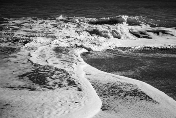 Black and white study of foamy waves overlapping on a beach on Hutchinson Island, Florida