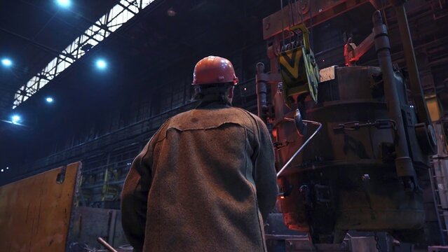 An Industrial Worker Concentrating on Operating Heavy Machinery Within a Factory Setting. Stock Clip