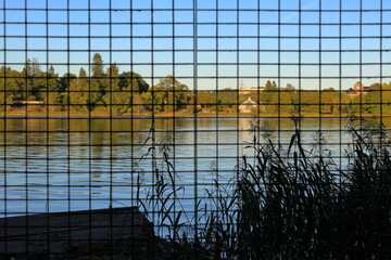 Prison concept with metal bars in nature. Brunnsviken lake at Hagaparken, Solna, Stockholm, Sweden. September 2024.