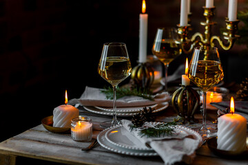 Elegant decor for Christmas family dinner. Center piece with burning candles, vintage chandelier. Zero waste eco-friendly reusable home decoration, fir tree branches. Cozy atmosphere, wooden furniture