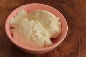 Natural homemade plain organic yogurt. Yoghurt in pink bowl on the wooden table. Fresh healty food.