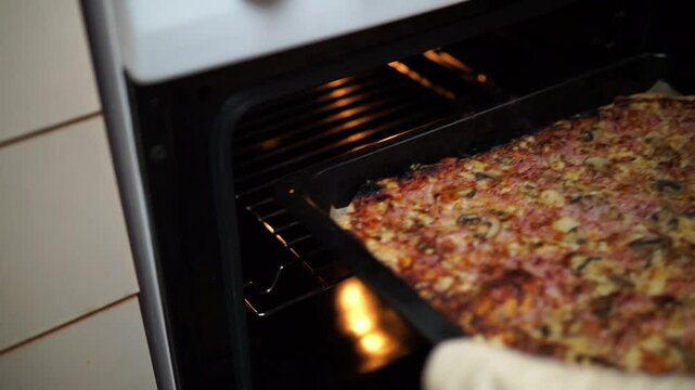 Woman's hands taking out homemade pizza from of oven