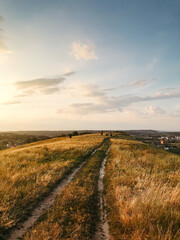 Dirt road on top of the hill range. Vanishing point track in hilly countryside field.	