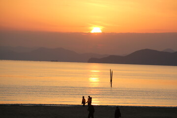 Fototapeta premium Image of people enjoying a beautiful sunset at Dadaepo Beach in Busan and a landscape image of sunset at sea 
