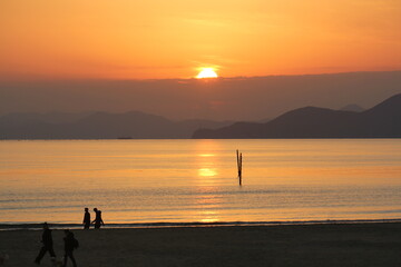 Image of people enjoying a beautiful sunset at Dadaepo Beach in Busan and a landscape image of sunset at sea
