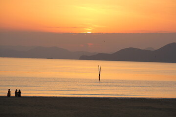 Fototapeta premium Image of people enjoying a beautiful sunset at Dadaepo Beach in Busan and a landscape image of sunset at sea 