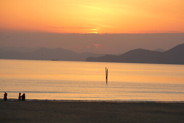 Image of people enjoying a beautiful sunset at Dadaepo Beach in Busan and a landscape image of sunset at sea
