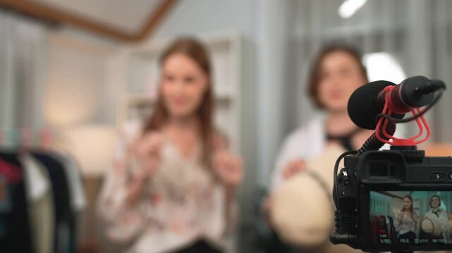 Rear view behide camera screen display two women influencer shoot vlog video review clothes prim social media or blog. Girls with apparel studio lighting for live streaming marketing recording session