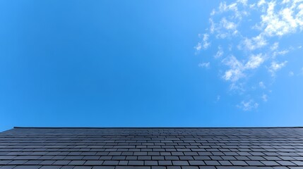 Image of an old gray shingled roof with a clear blue sky in the background