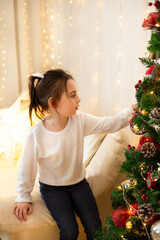 Five year old girl plays and has fun near the Christmas tree