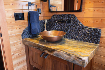 Elegant vanity with brass vessel sink and stone backsplash