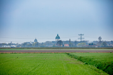 Rural Dutch landscape with fields, a church, and power lines.  Calm, overcast day.
