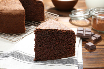 Piece of tasty chocolate sponge cake on wooden table, closeup