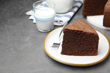 Piece of tasty chocolate sponge cake served on grey table. Space for text