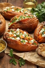 Tasty cooked sweet potatoes with feta cheese, green onion and parsley on wooden table, closeup
