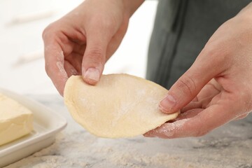 Woman making pirozhki (stuffed pastry pies) at white marble table indoors, closeup