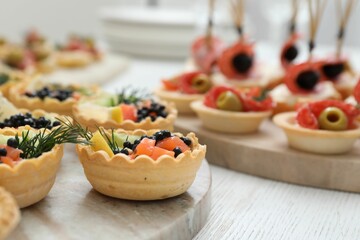 Many different tasty canapes on white wooden table, closeup