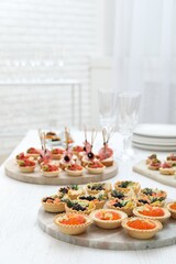 Many different tasty canapes on white wooden table, closeup