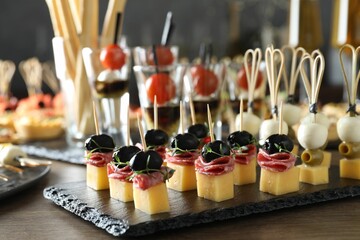 Many different tasty canapes on wooden table, closeup