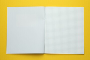 Open copybook on yellow background, top view